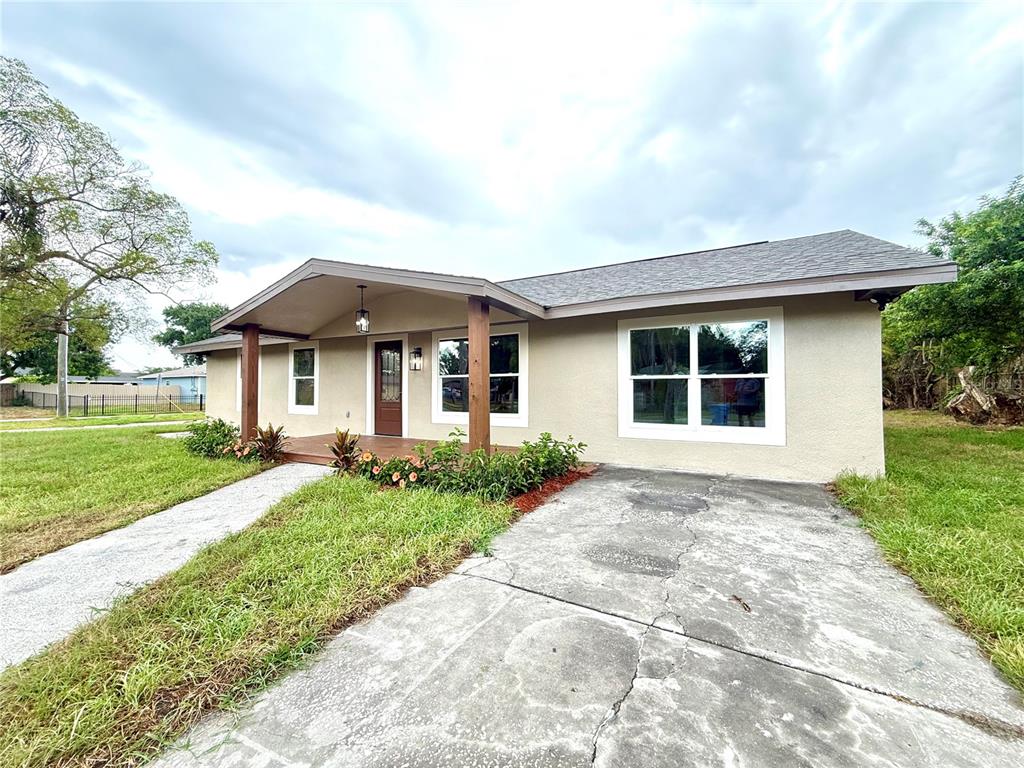 A single-story house with a covered porch, concrete driveway, and tan stucco exterior — 1427 MURILLO LOOP, RUSKIN, FL