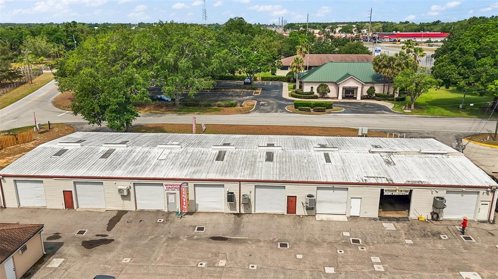 An aerial view shows a long, single-story commercial building with multiple garage bays and parking — 3101 KURT STREET, EUSTIS, FL