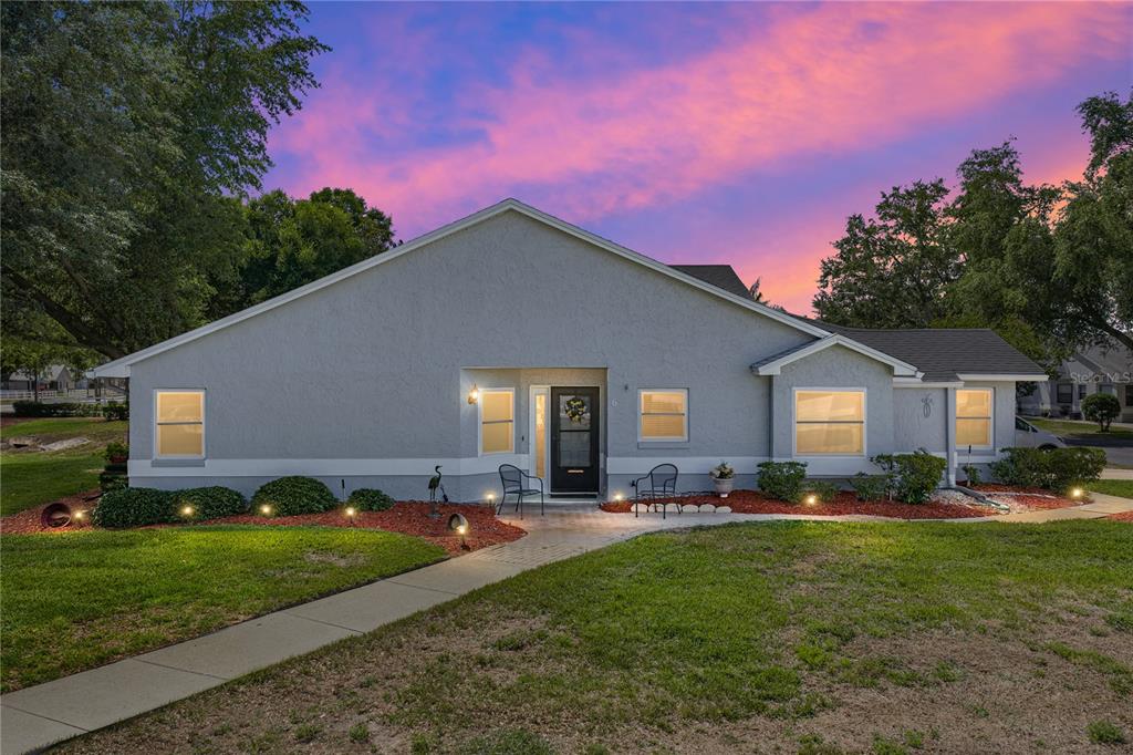 The exterior of a single-story house features a patio, lawn, and red mulch landscaping — 6380 EGRET DRIVE UNIT 6, LAKELAND, FL