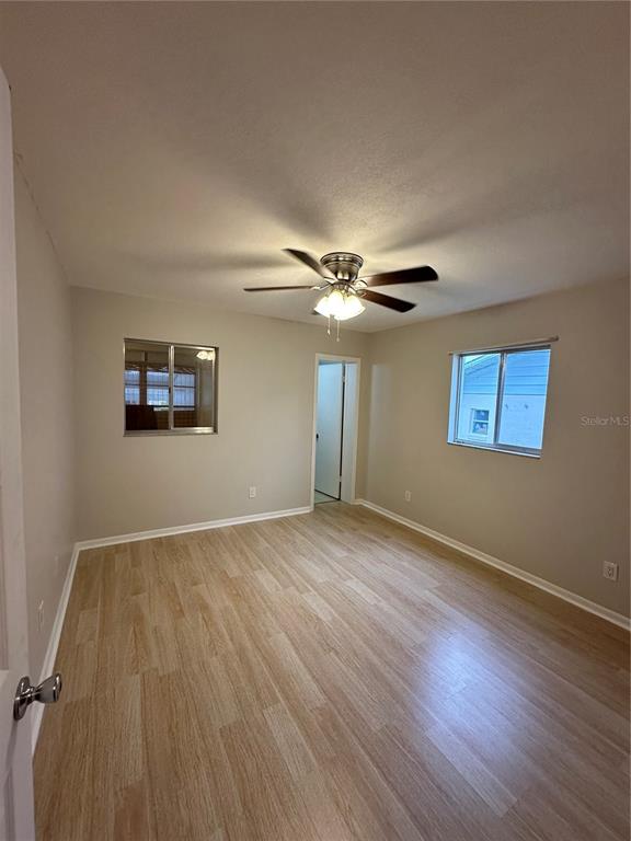 An empty bedroom features light-colored wood-look flooring, a ceiling fan, and two windows — 3125 VILLA ROAD, SEBRING, FL