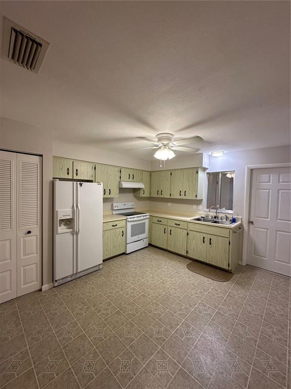 A kitchen features light green cabinets, white appliances, and patterned vinyl flooring — 3125 VILLA ROAD, SEBRING, FL
