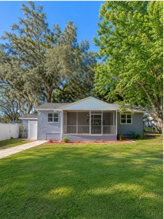 A single-story house with a screened-in front porch and gray siding sits on a grassy lawn — 130 E DICIE AVENUE, EUSTIS, FL