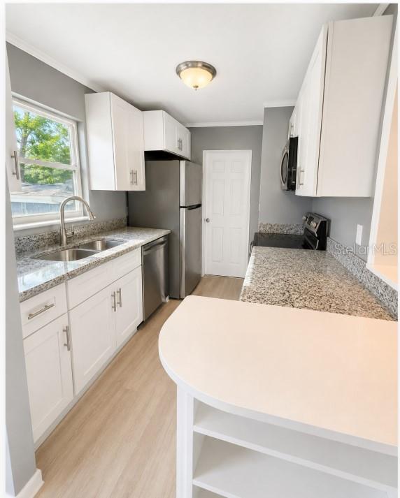 A kitchen with white cabinets, granite countertops, stainless steel appliances, and light wood-look flooring — 130 E DICIE AVENUE, EUSTIS, FL