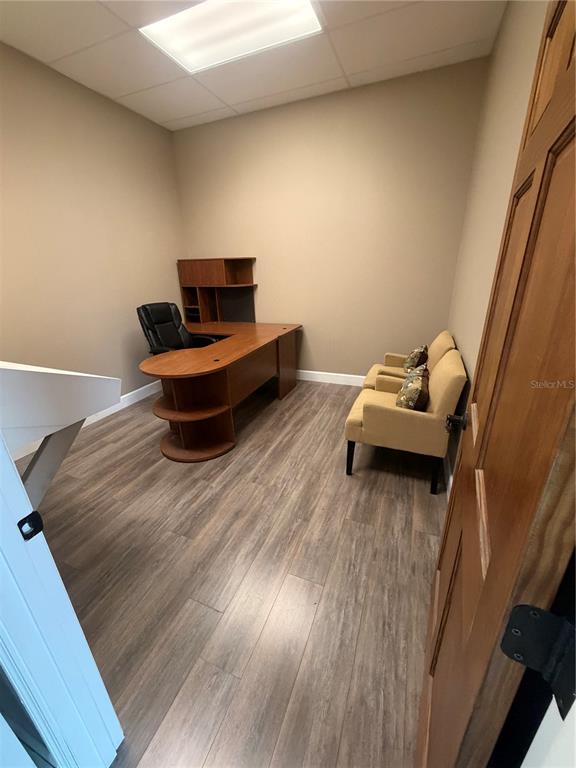 An office features a wooden desk, two tan chairs, and wood-look flooring — 910 BELLE AVENUE UNIT 1140, WINTER SPRINGS, FL