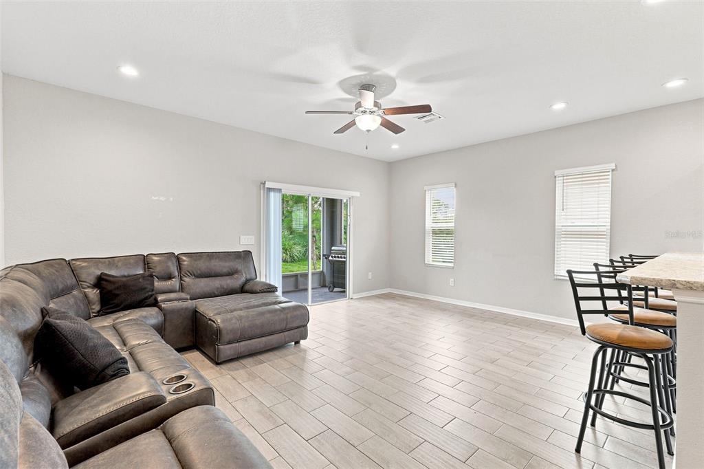 A living room features a gray sectional sofa, tile flooring, and a sliding glass door — 4641 VIGNETTE WAY, SARASOTA, FL