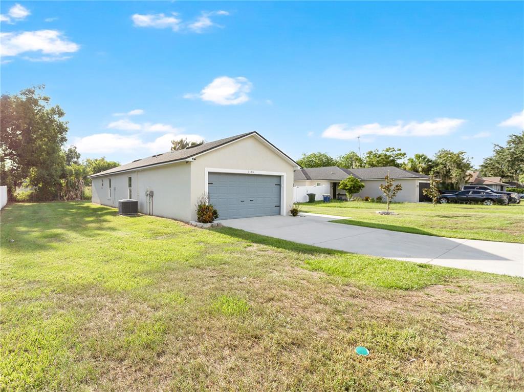 A bright, empty room features light wood-look flooring, a kitchen island, and sliding glass doors — 1185 FAIRVIEW AVENUE, BARTOW, FL