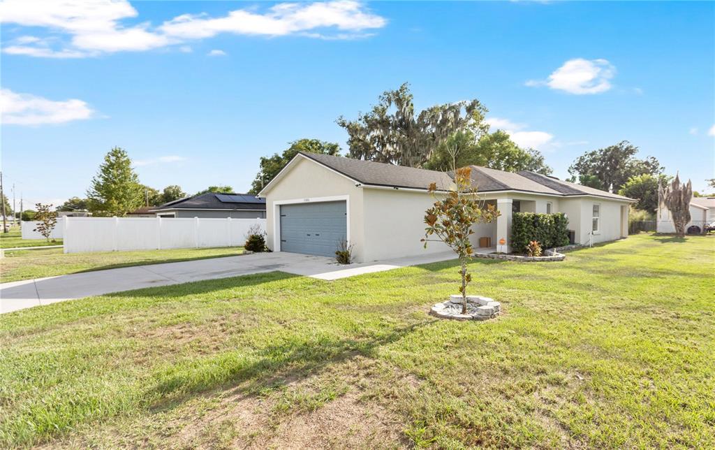 An open-concept kitchen with white cabinets and stainless steel appliances overlooks a spacious living area — 1185 FAIRVIEW AVENUE, BARTOW, FL