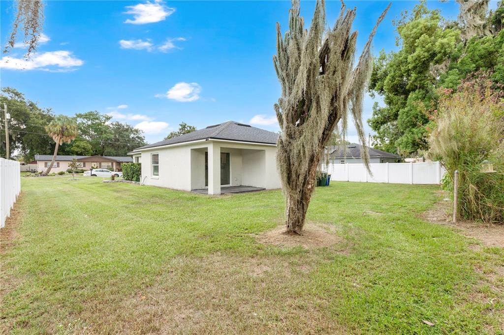 A kitchen with white cabinets, granite countertops, stainless steel appliances, and a stone tile backsplash — 1185 FAIRVIEW AVENUE, BARTOW, FL