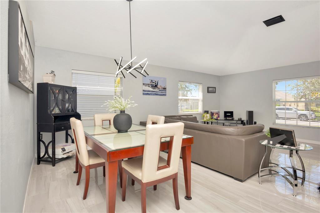 A dining area with a glass-top table and a living room with a gray sofa — 2239 ROANOKE SPRINGS DRIVE, RUSKIN, FL