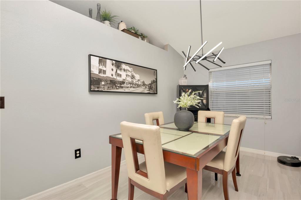 A dining room features a glass-topped table, four upholstered chairs, and a modern light fixture — 2239 ROANOKE SPRINGS DRIVE, RUSKIN, FL
