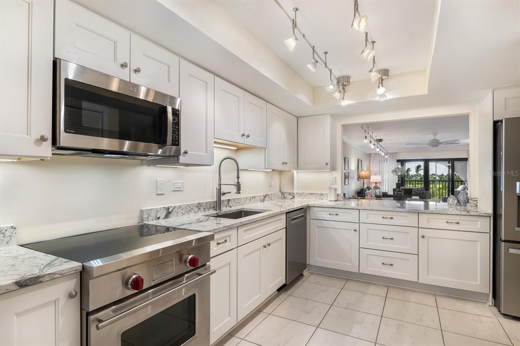 A modern kitchen features white cabinets, stainless steel appliances, and marble countertops — 950 PALM AVENUE UNIT 304, BOCA GRANDE, FL