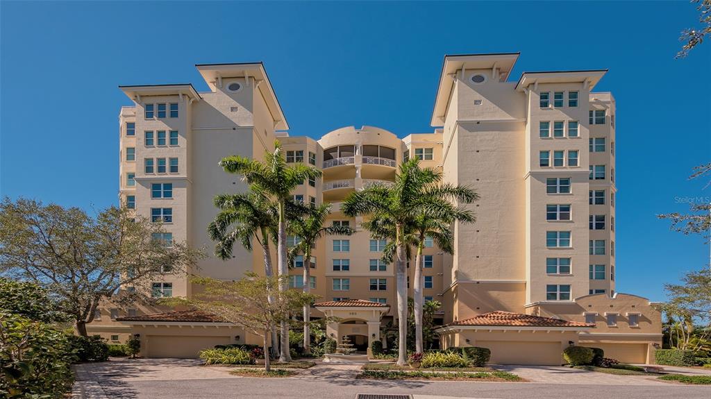 A multi-story beige residential building with palm trees and a paved driveway in front — 385 N POINT ROAD UNIT 503, OSPREY, FL