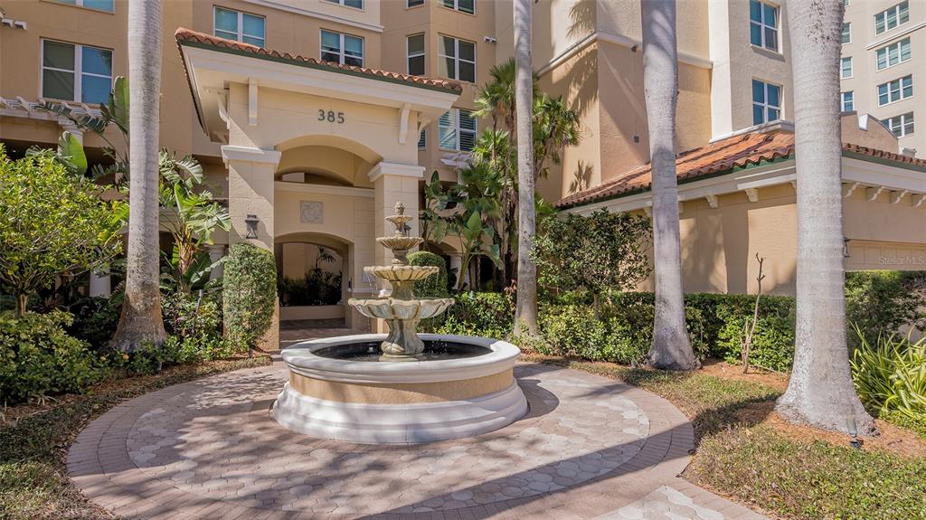A multi-tiered stone fountain sits in front of a building entrance with palm trees — 385 N POINT ROAD UNIT 503, OSPREY, FL