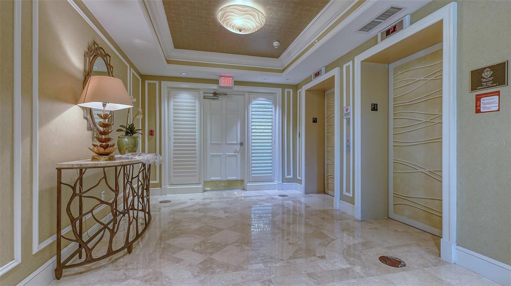 An elevator lobby features marble floors, a decorative console table, and a coffered ceiling — 385 N POINT ROAD UNIT 503, OSPREY, FL