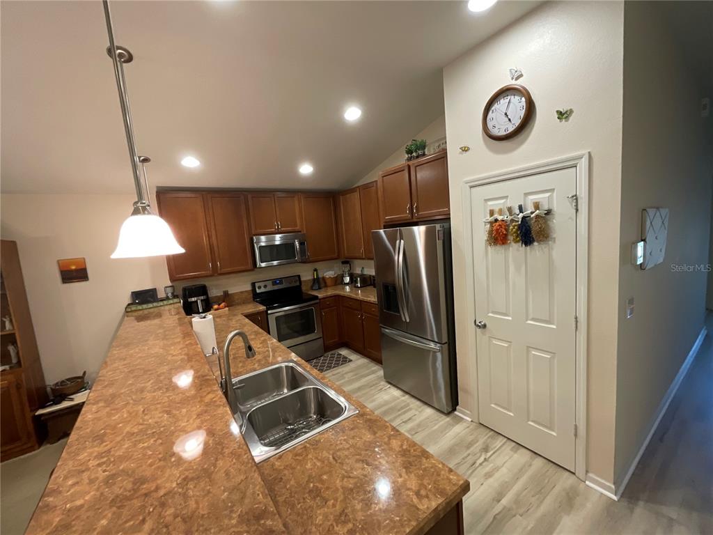 A kitchen features wood cabinets, stainless steel appliances, and a brown laminate countertop — 151 PERGOLA PLACE, ORMOND BEACH, FL