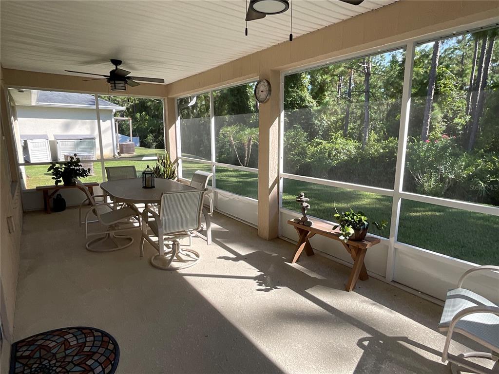 A screened-in porch features a dining set, a wooden bench, and views of a backyard — 151 PERGOLA PLACE, ORMOND BEACH, FL