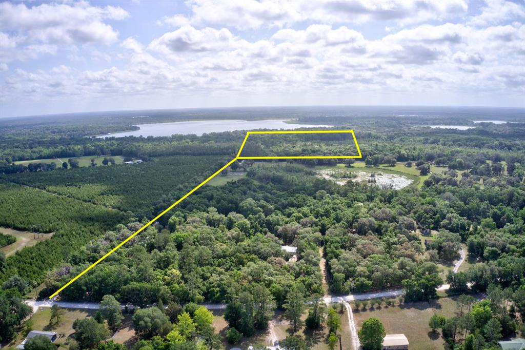 An aerial view shows a rectangular plot of land outlined in yellow near a lake — 8903 SE 225TH DRIVE, HAWTHORNE, FL