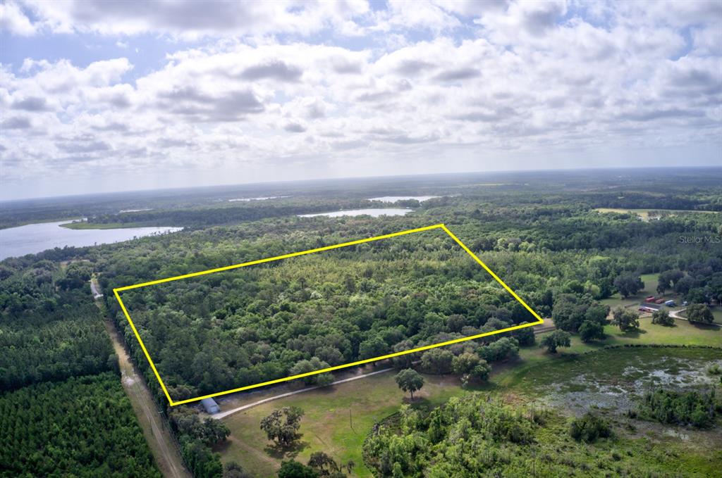 An aerial view shows a rectangular plot of land outlined in yellow amidst wooded terrain — 8903 SE 225TH DRIVE, HAWTHORNE, FL