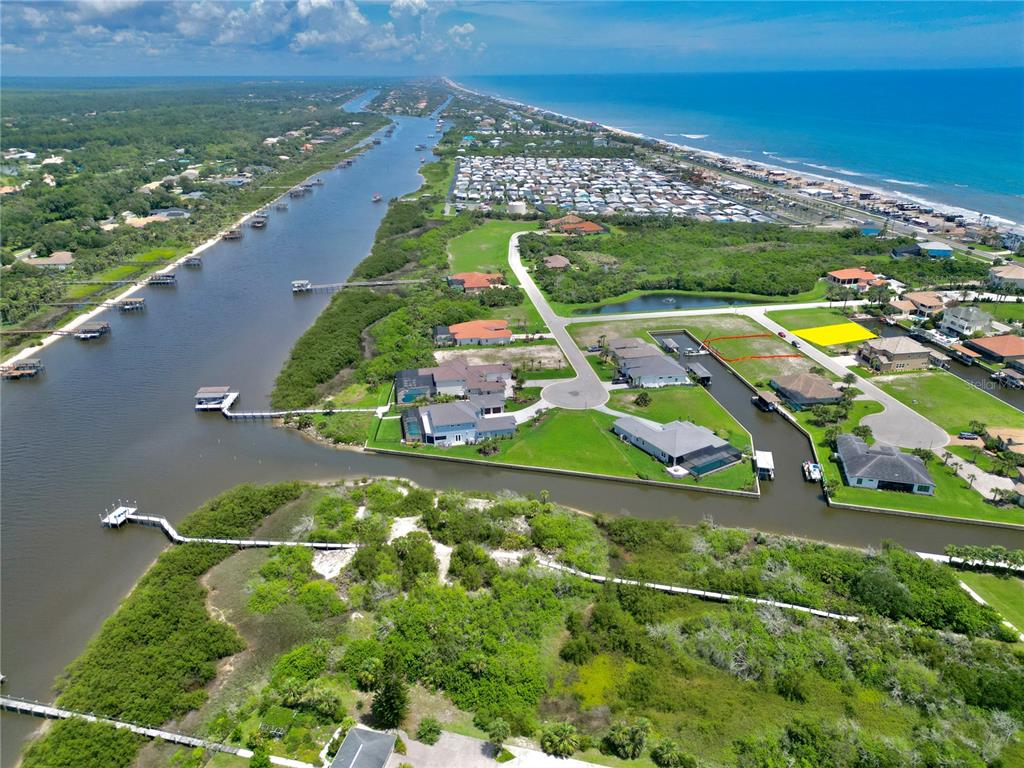 An aerial view shows waterfront homes, a canal, and a vacant lot near the ocean — 62 MALIBU COVE, BEVERLY BEACH, FL