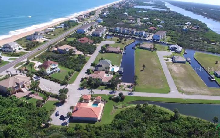 An aerial view of a coastal neighborhood featuring houses, canals, and a nearby beach — 62 MALIBU COVE, BEVERLY BEACH, FL