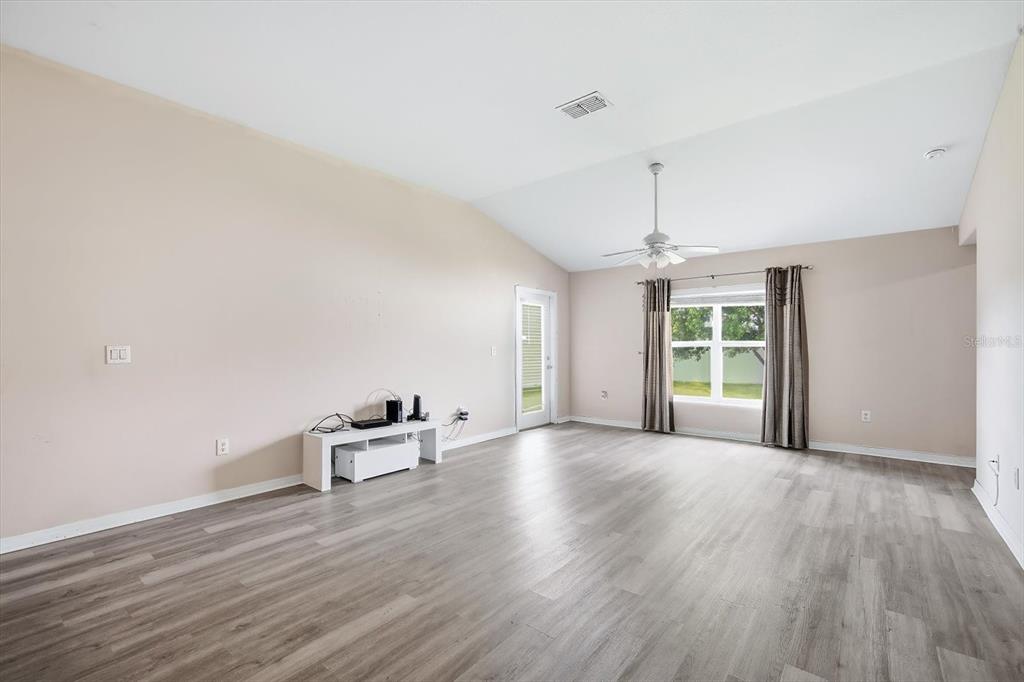 A living room with light-colored walls, wood-look flooring, a ceiling fan, and a glass door — 3781 MADBURY CIRCLE, LAKELAND, FL