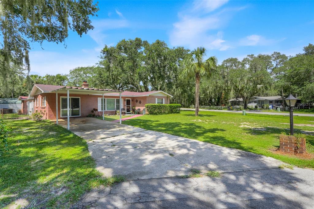 A single-story brick house with a carport and a large front lawn under mature trees — 11031 W BEACH PARKWAY, LAKE WALES, FL