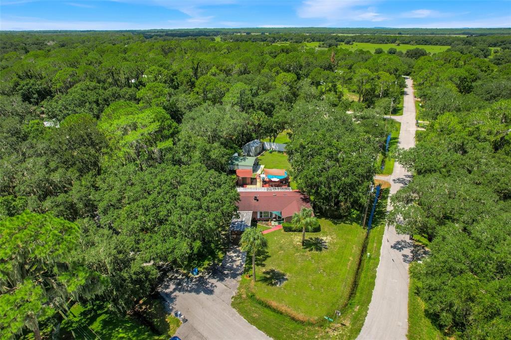 An aerial view shows a house with a red roof surrounded by trees and grass — 11031 W BEACH PARKWAY, LAKE WALES, FL