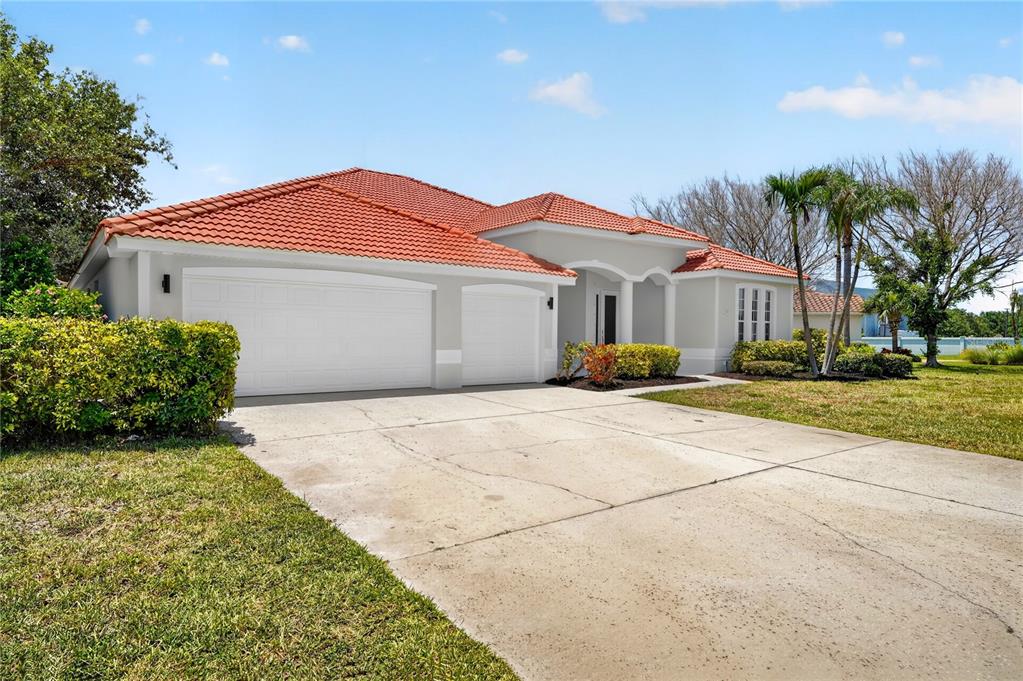 A single-story house with a red tile roof, white stucco walls, and a concrete driveway — 572 OCEANSIDE BOULEVARD, MELBOURNE, FL