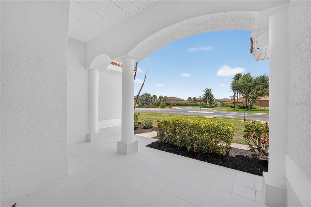 A covered white-tiled porch features arched openings supported by columns overlooking a suburban street — 572 OCEANSIDE BOULEVARD, MELBOURNE, FL
