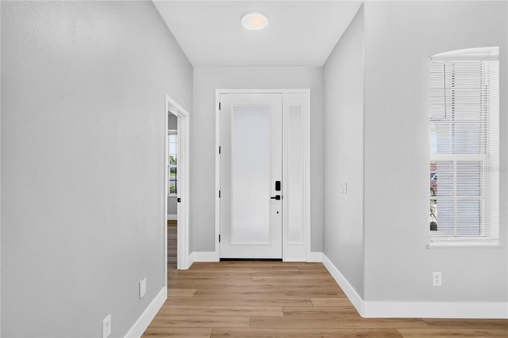 A bright entryway features light gray walls, wood-look flooring, a white front door, and a window — 572 OCEANSIDE BOULEVARD, MELBOURNE, FL