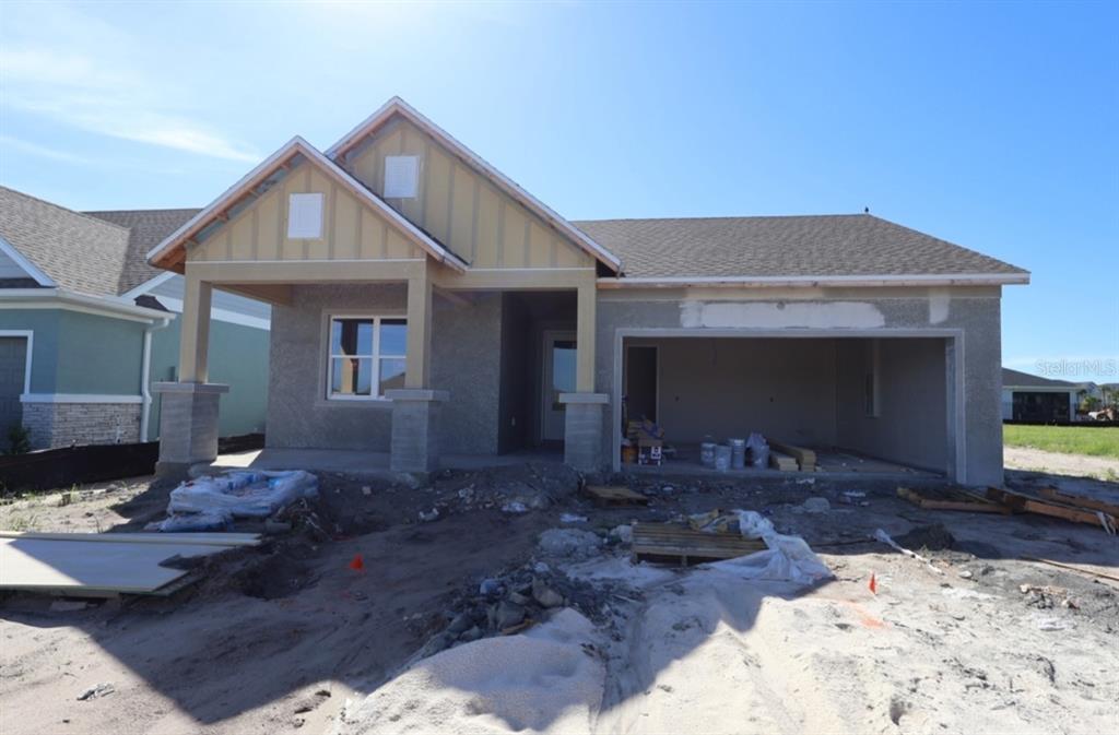 A single-story house under construction with a covered porch, stucco exterior, and an open garage — 5157 CREEK SAND DRIVE, APOLLO BEACH, FL