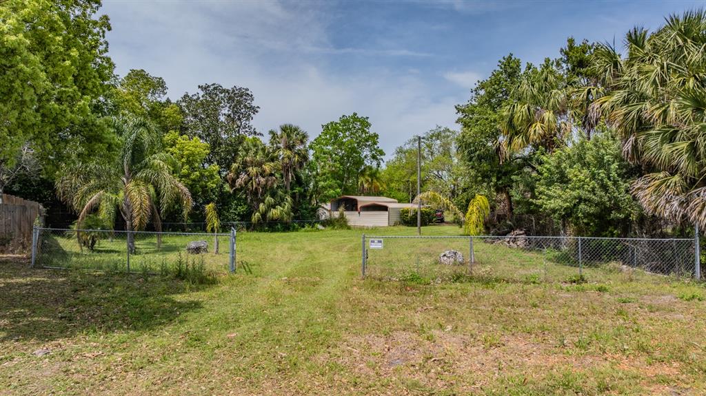 A grassy lot features a chain-link fence, several palm trees, and a small shed behind — 0 VILLA DRIVE, HUDSON, FL