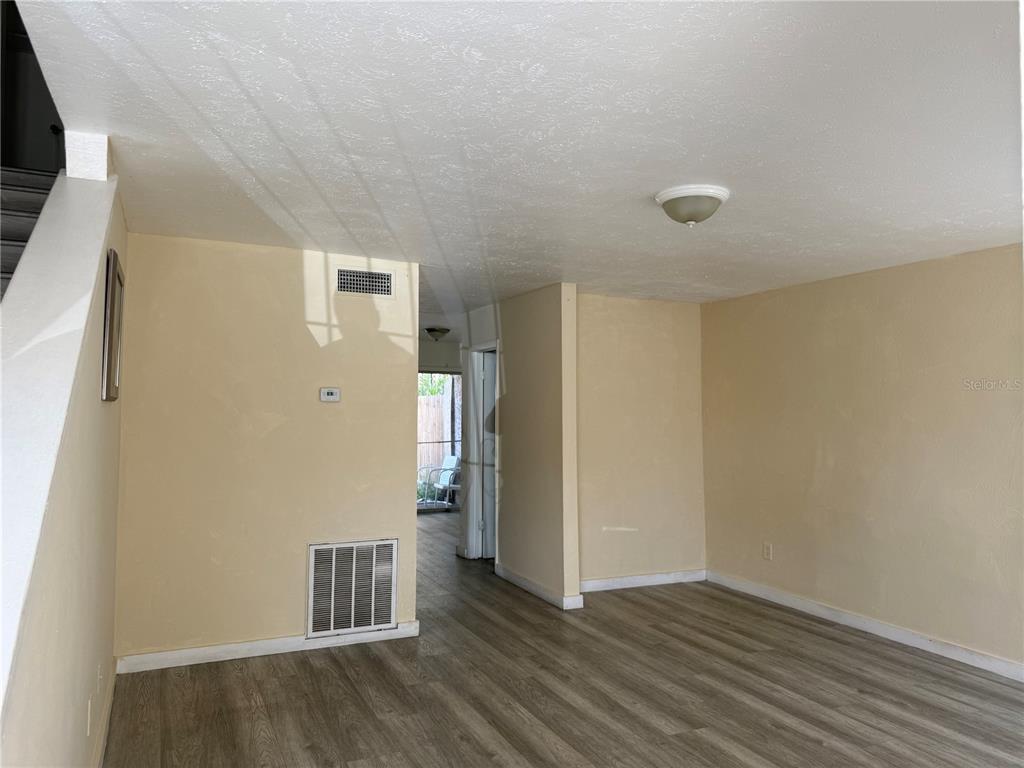 A living room with light wood-look flooring, a sofa, a computer desk, and a staircase — 4004 BARWOOD DRIVE UNIT 3804, ORLANDO, FL
