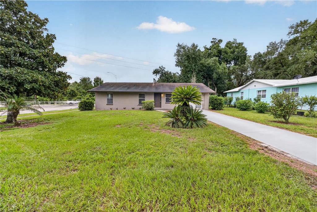 A single-story house with a gray exterior, a concrete driveway, and a large front lawn — 507 S OHIO AVE, GROVELAND, FL