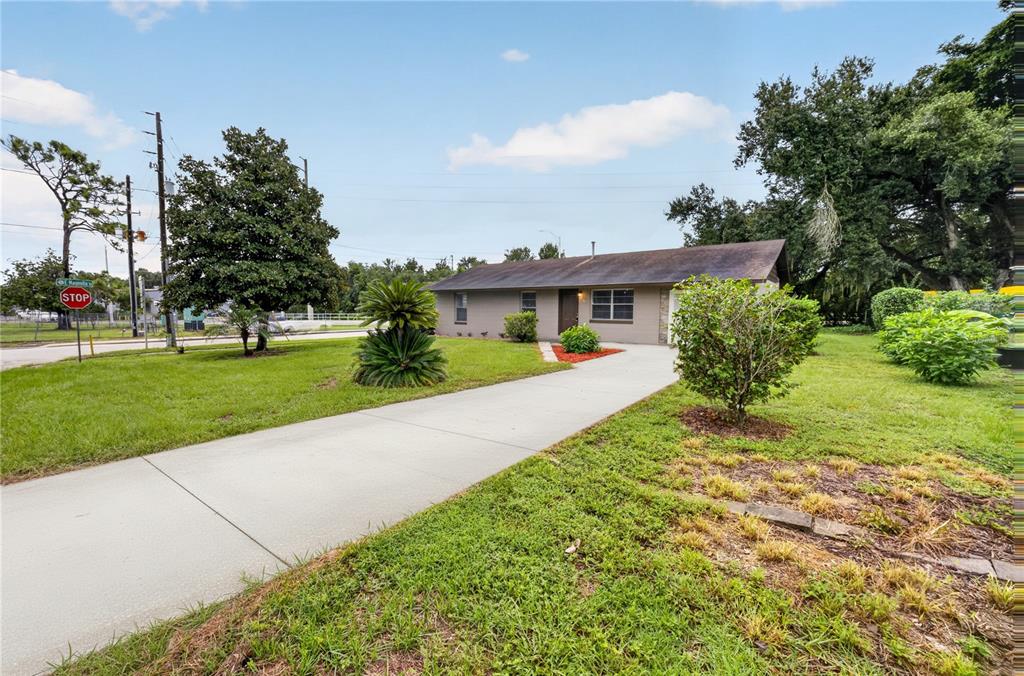 A single-story house with a gray exterior and a concrete driveway sits on a lawn — 507 S OHIO AVE, GROVELAND, FL