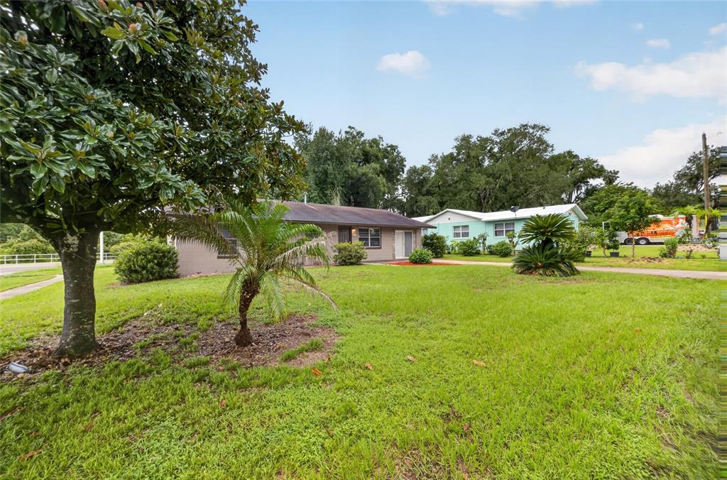 A single-story house with a brown exterior sits on a grassy lot with mature trees — 507 S OHIO AVE, GROVELAND, FL