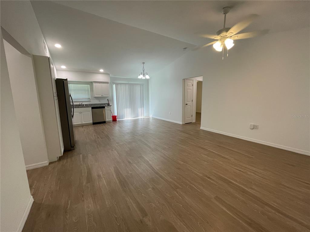 An open-concept living and dining area features light wood-look flooring and a kitchen with white cabinets — 2811 GARFIELD STREET W, INVERNESS, FL