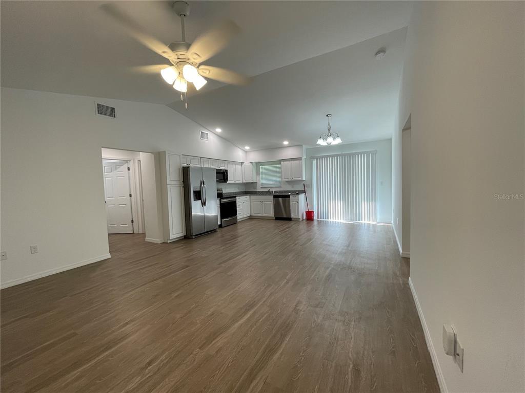An open-concept kitchen and living area features white cabinetry, stainless steel appliances, and wood-look flooring — 2811 GARFIELD STREET W, INVERNESS, FL
