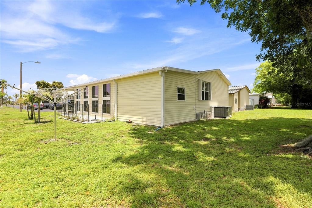 A side view of a light yellow manufactured home with a fenced patio area — 1 POINSETTIA DRIVE, FORT MYERS, FL
