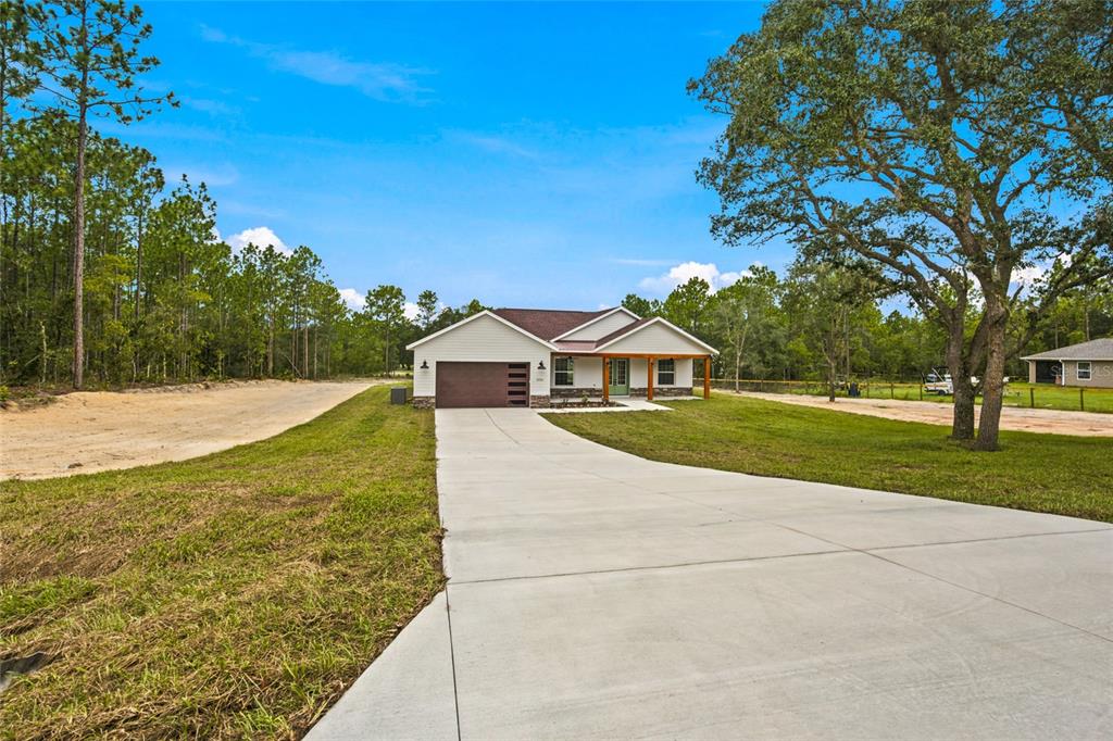 A single-story house with a concrete driveway, a two-car garage, and a covered front porch — 8396 SW 125TH CT ROAD, DUNNELLON, FL