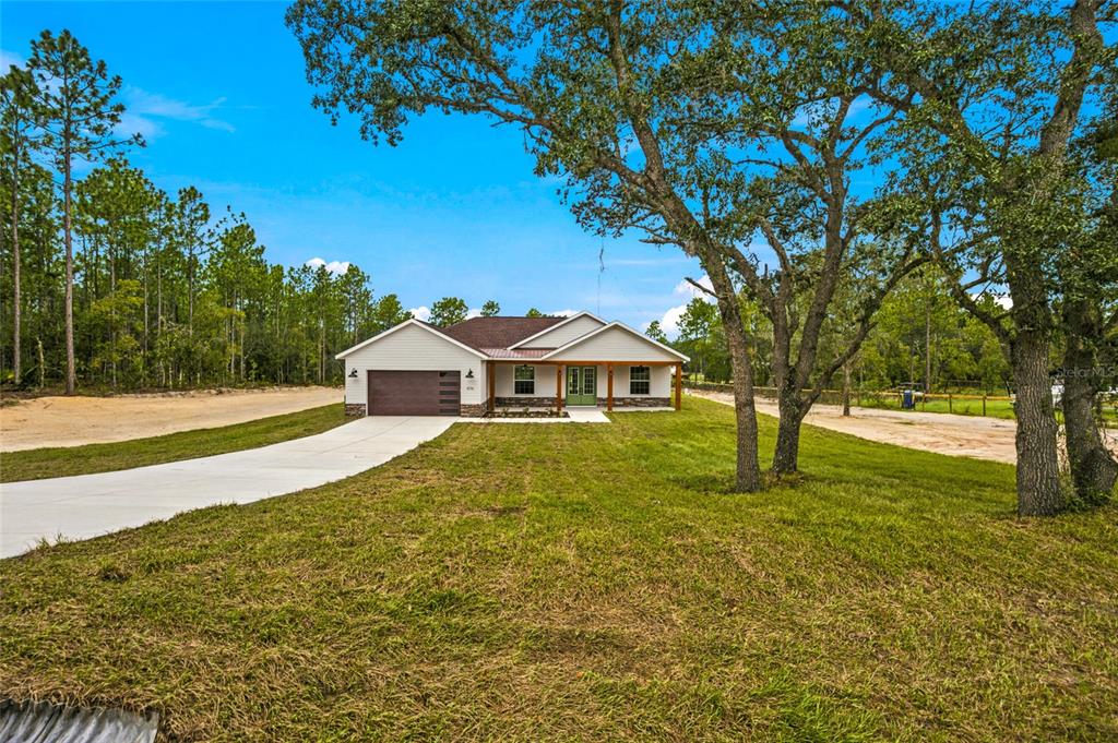 A single-story house with a brown garage door and a covered porch stands on grass — 8396 SW 125TH CT ROAD, DUNNELLON, FL