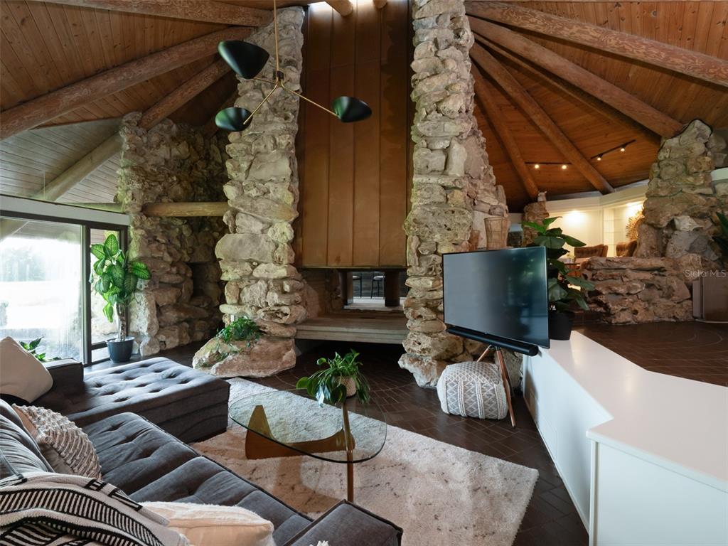 A living room features a large stone fireplace, vaulted wood ceiling, and a dark sofa — 8351 NW 110TH STREET, REDDICK, FL