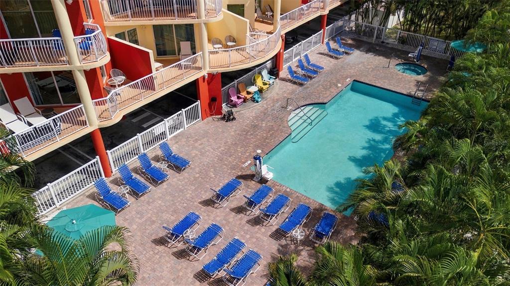 An aerial view shows a multi-story green hotel building with orange roofs near the beach — 11605 GULF BOULEVARD UNIT 502, TREASURE ISLAND, FL