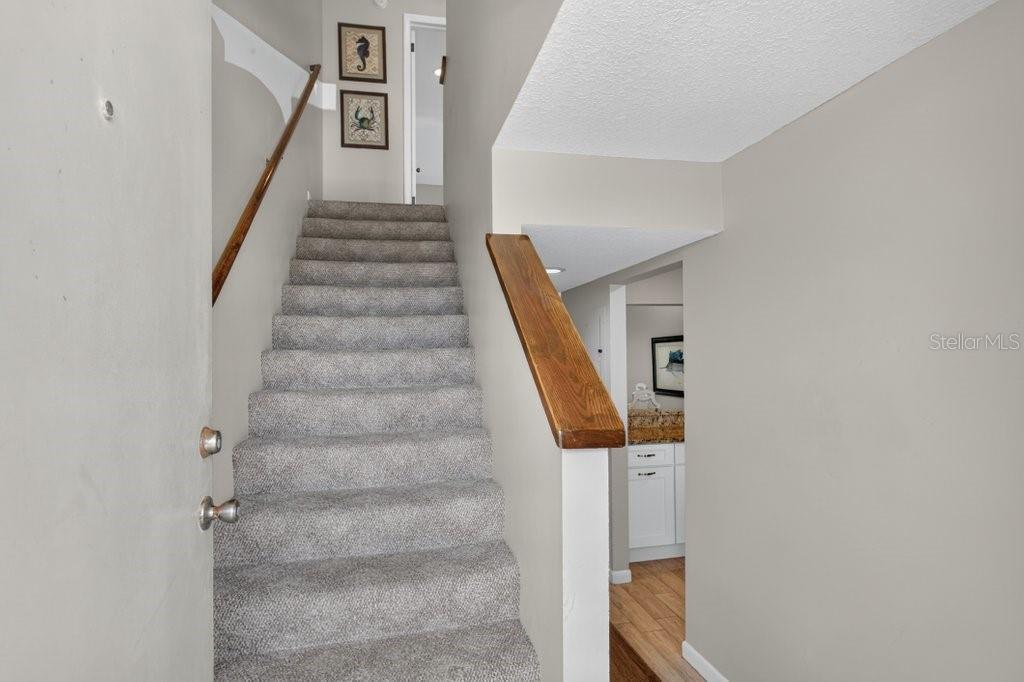 A carpeted staircase leads to an upper landing with two framed pictures on the wall — 8550 A1A S UNIT 14250, ST AUGUSTINE, FL