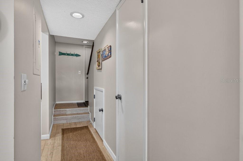 A hallway with light wood-look flooring leads to a small set of stairs — 8550 A1A S UNIT 14250, ST AUGUSTINE, FL