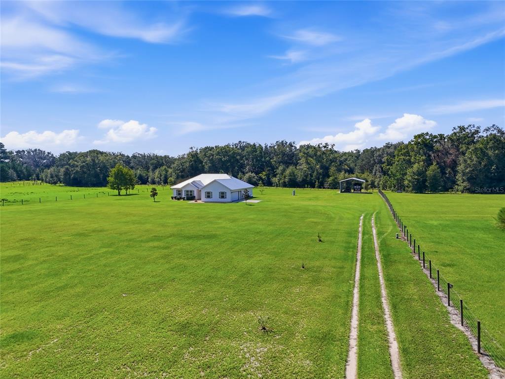 A white house sits in the middle of a large, fenced grassy field — 5600 SW COUNTY ROAD 240, LAKE CITY, FL