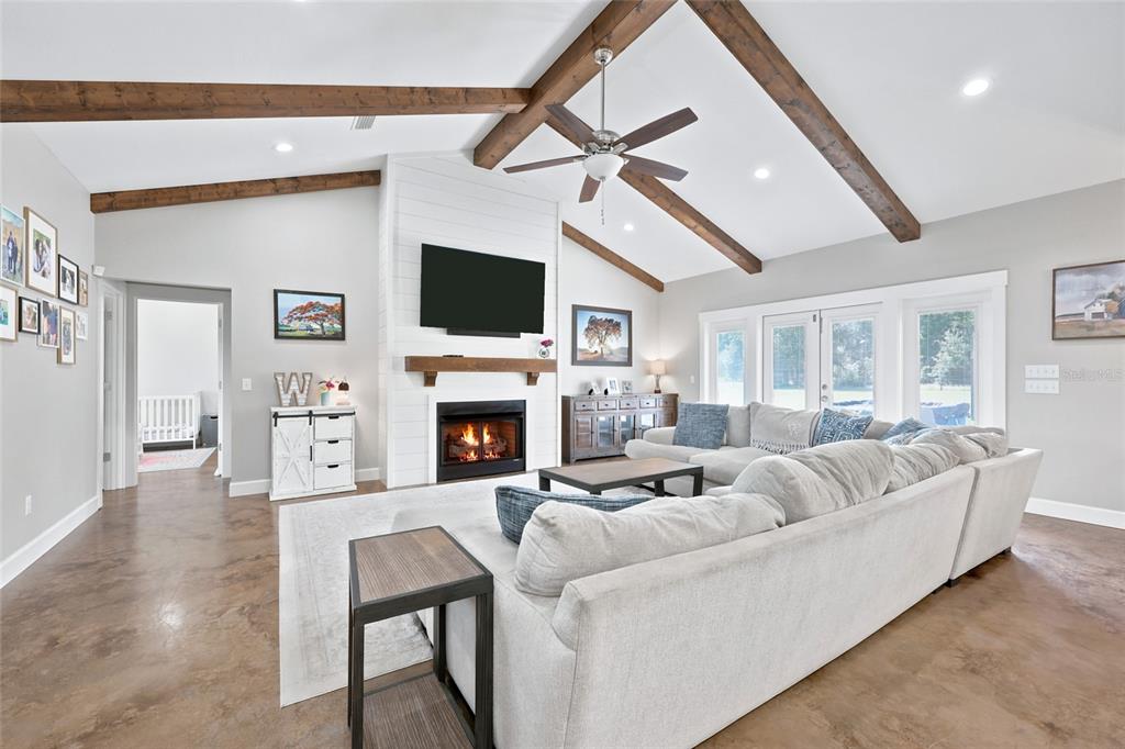 A living room features a vaulted ceiling with exposed beams, a fireplace, and a sectional sofa — 5600 SW COUNTY ROAD 240, LAKE CITY, FL