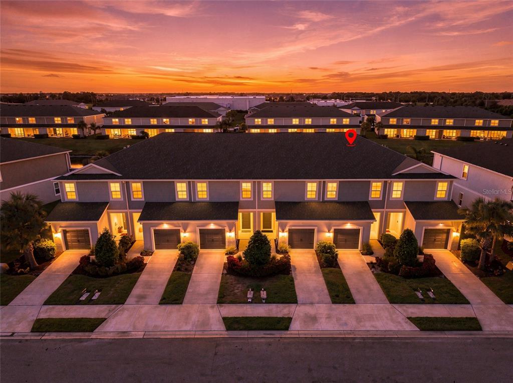 An aerial view of a multi-unit townhouse complex at sunset with a red location pin — 8514 CANYON CREEK TRAIL, PARRISH, FL