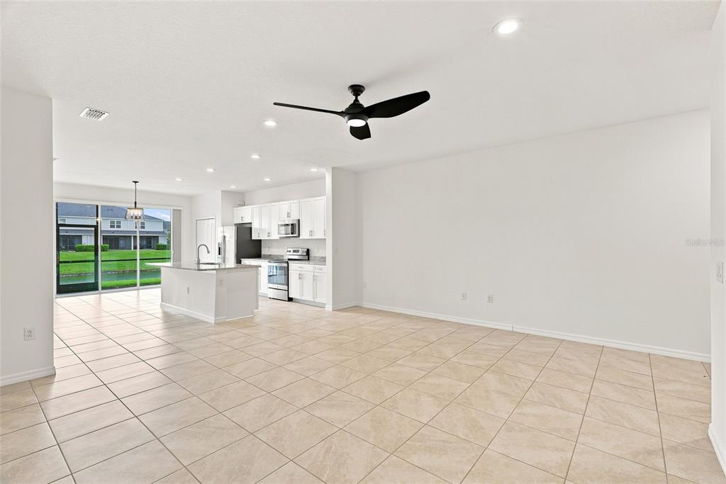 An open-concept kitchen and living area features white cabinetry, tile flooring, and a ceiling fan — 8514 CANYON CREEK TRAIL, PARRISH, FL