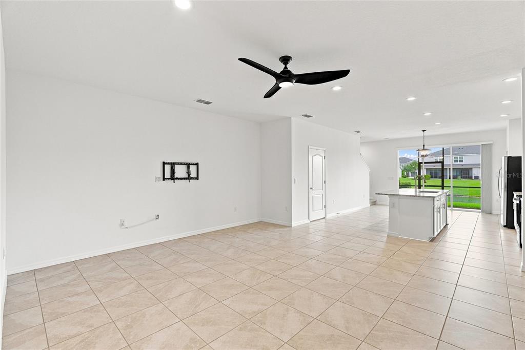 An open-concept living and kitchen area features white walls, tile flooring, and a ceiling fan — 8514 CANYON CREEK TRAIL, PARRISH, FL